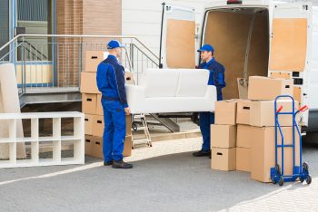 Movers carrying sofa outside truck on street