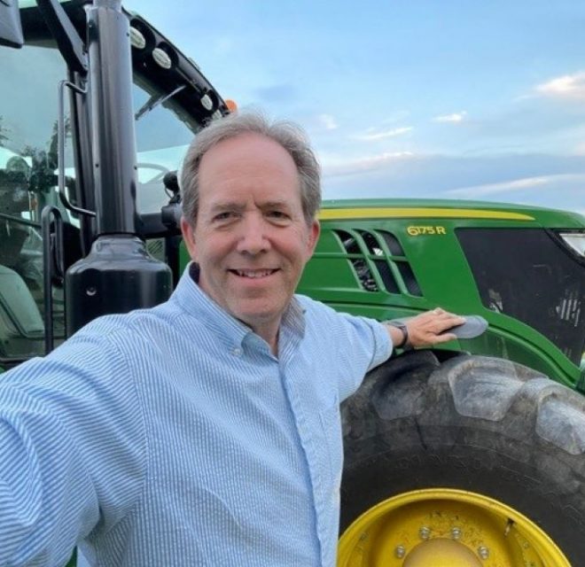 Man smiling in front of a tractor
