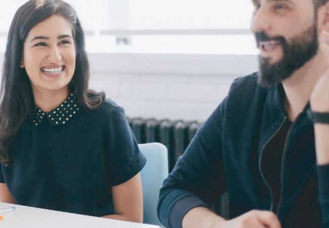 Man and woman coworkers laughing at meeting