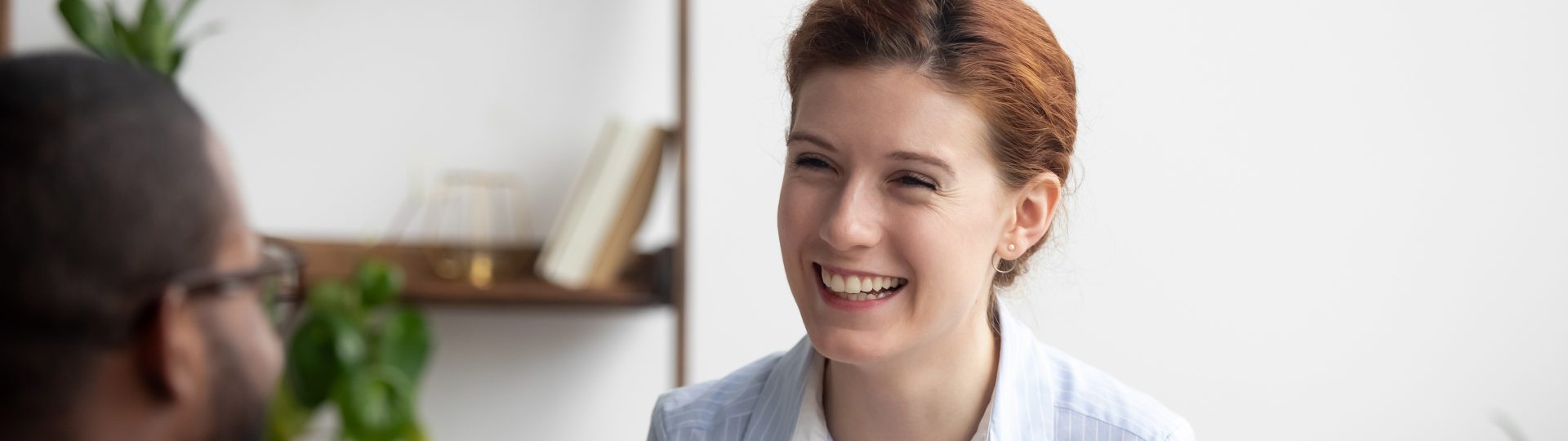 Friendly woman speaking with coworking while sitting at desk