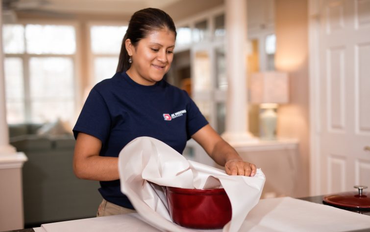 Young Hispanic woman packing kitchenware