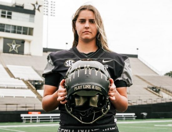 Photo of Sarah Fuller holding her football helmet that has "play like a girl" written on it