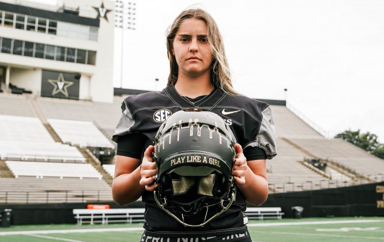 Photo of Sarah Fuller holding her football helmet that has "play like a girl" written on it