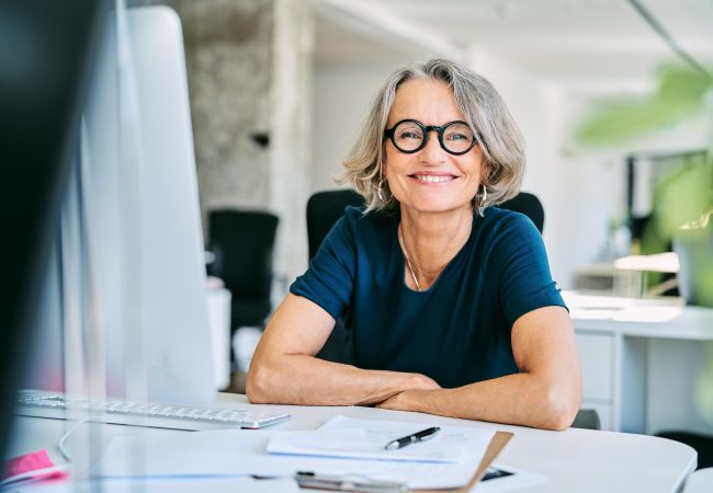 Woman sitting at desk at work smiling at the camera