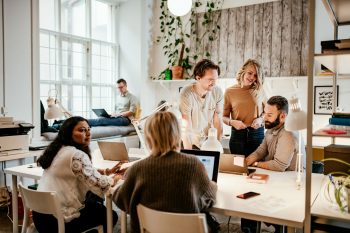 Diverse group of happy employees gathered around a table in a modern office