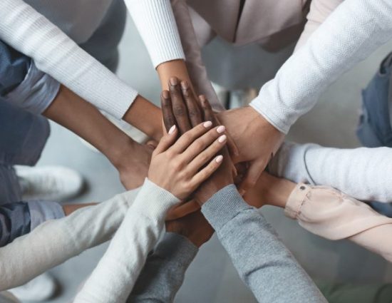 Close up of international business team showing unity with putting their hands together on top of each other. Concept of teamwork, top view