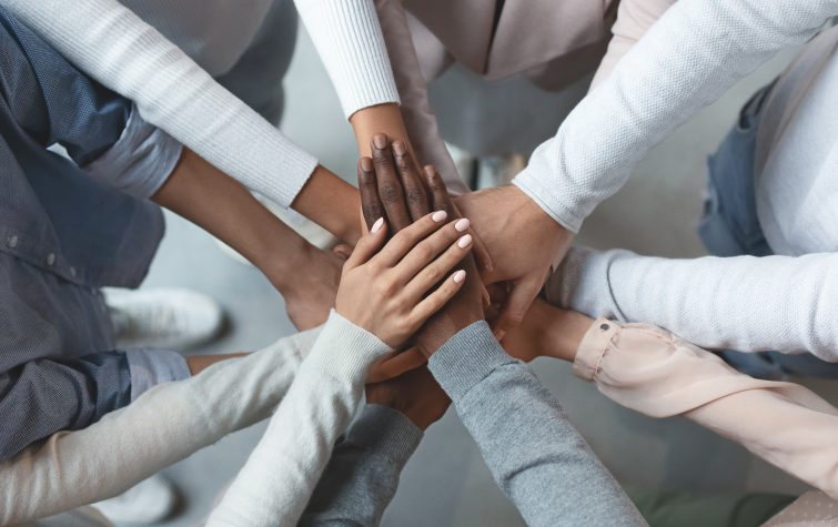 Close up of international business team showing unity with putting their hands together on top of each other. Concept of teamwork, top view