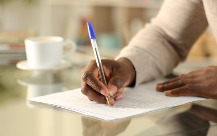 Close up of hands filling out form on a desk