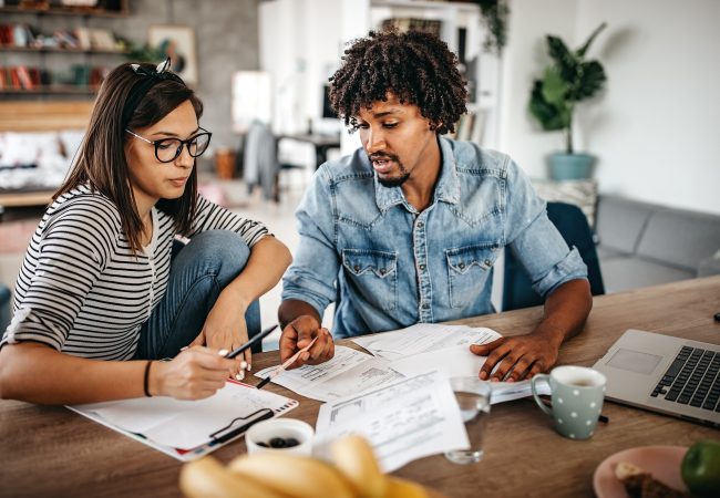 Modern married multi-ethnic young couple calculating financial bills at home