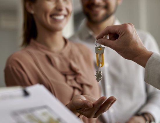 Close-up of couple receiving new house keys from real estate agent.