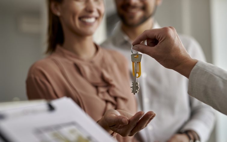 Close-up of couple receiving new house keys from real estate agent.
