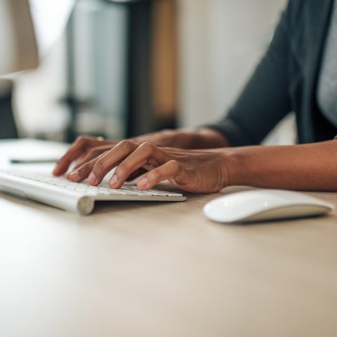 Businesswoman typing on wireless keyboard, close-up.