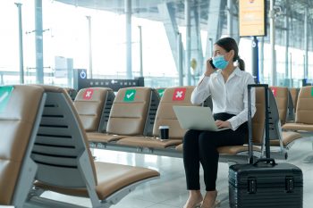 Woman sitting in airport talking on cell phone and using laptop