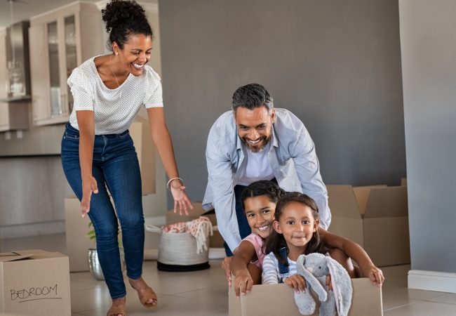 Young Indian father playing with his two kids in moving boxes after moving in to new home
