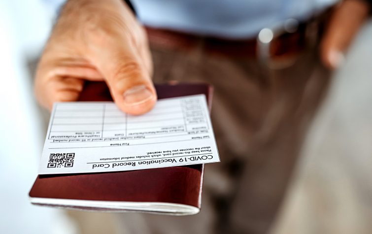 Man handing over passport and vaccine card because he is traveling