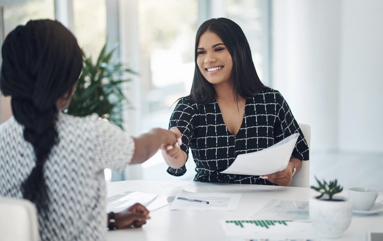 Shot of two young businesswomen shaking hands in a modern office