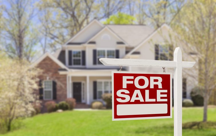 For Sale sign in front of large house