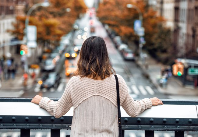 Woman standing on bridge overlooking the city streets