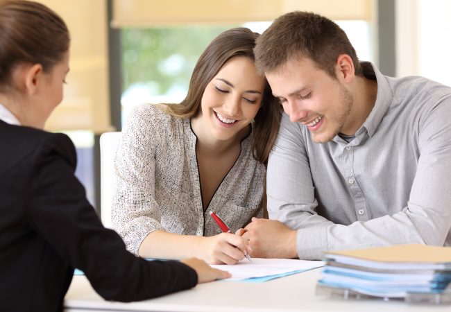 A man and a woman sitting closely together signing papers