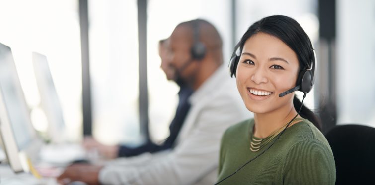 Portrait of a call centre agent working alongside her colleagues in an office