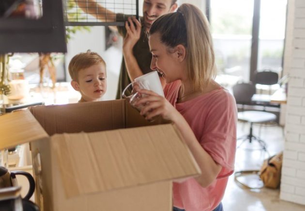 Photo of a young family with a little boy, unpacking essentials in the kitchen of their new home