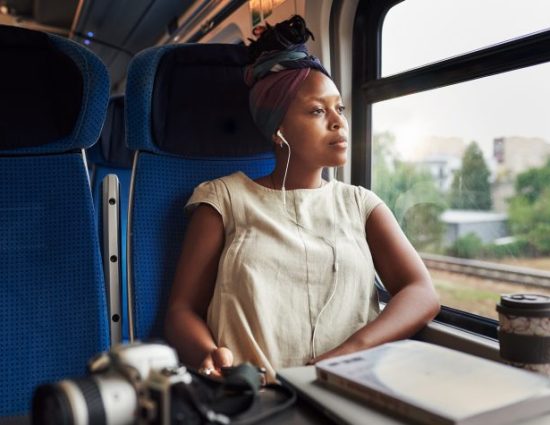 Woman with earbuds in looking out a train window