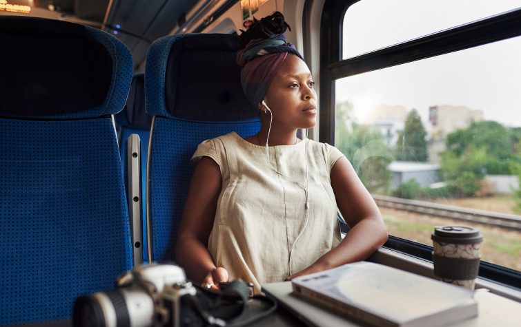 Woman with earbuds in looking out a train window