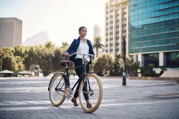 Young businesswoman traveling with a bicycle through the city