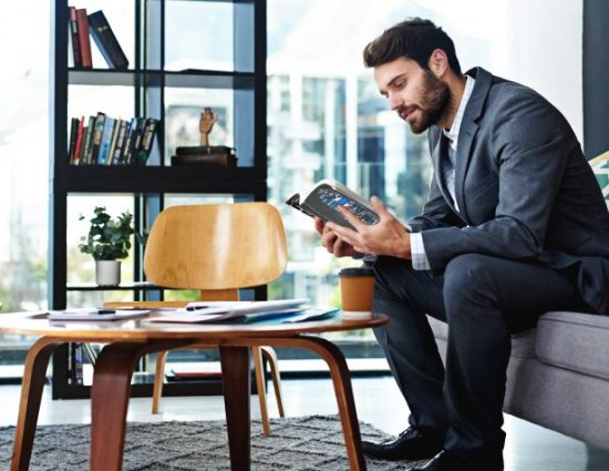Shot of a young businessman reading a book in a modern office