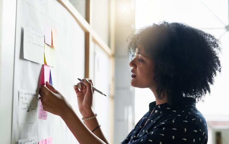 businesswoman writing on sticky notes on white board