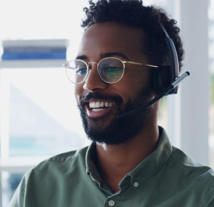 young african american man working at computer while talking on headset