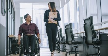 Man in wheelchair and woman coworkers roam office together