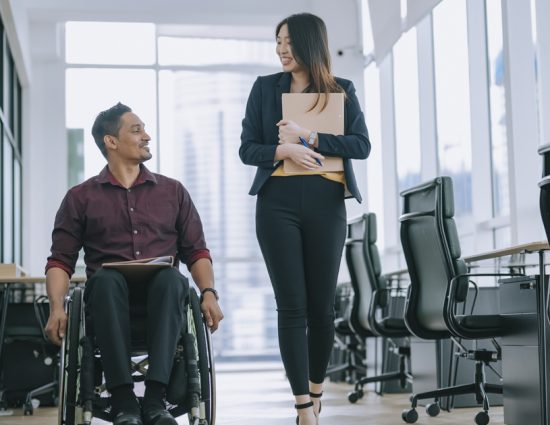 Man in wheelchair and woman coworkers roam office together