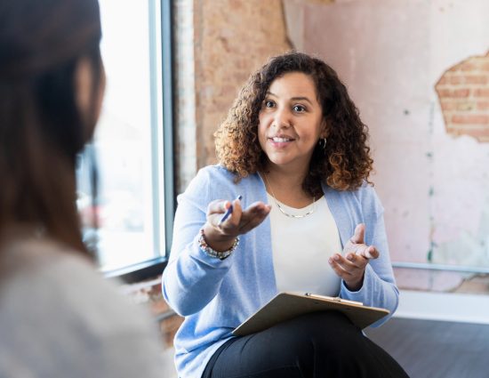 Woman with a clipboard talking to a coworker