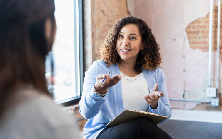 Woman with a clipboard talking to a coworker