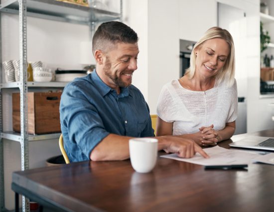 Man and woman smiling while signing a document