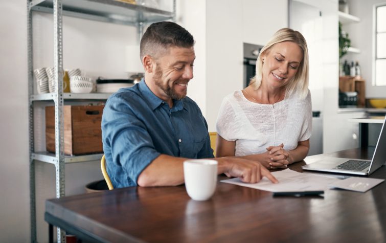 Man and woman smiling while signing a document