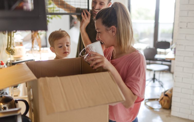 Photo of a young family with a little boy, unpacking essentials in the kitchen of their new home