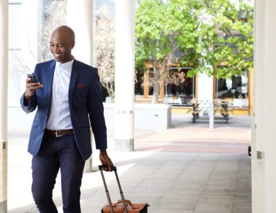 businessman in suit walking with a suitcase outside of a business building