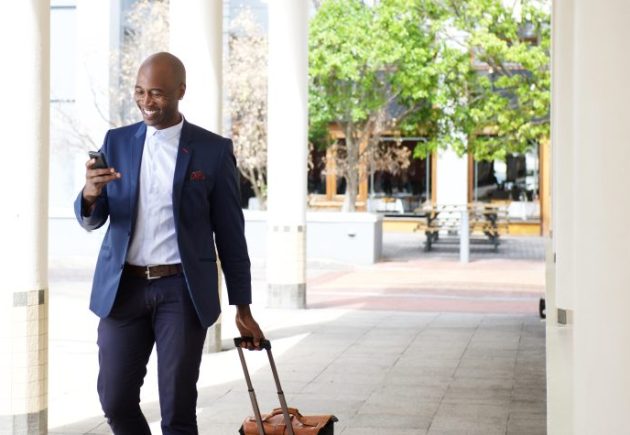 businessman in suit walking with a suitcase outside of a business building