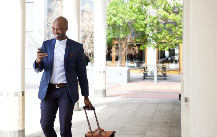 businessman in suit walking with a suitcase outside of a business building