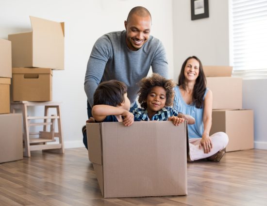 a dad jokingly pushes 2 kids around home in a moving box