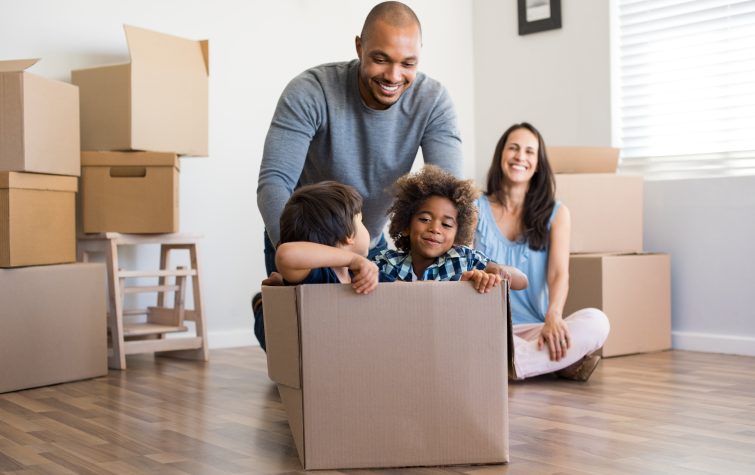 a dad jokingly pushes 2 kids around home in a moving box