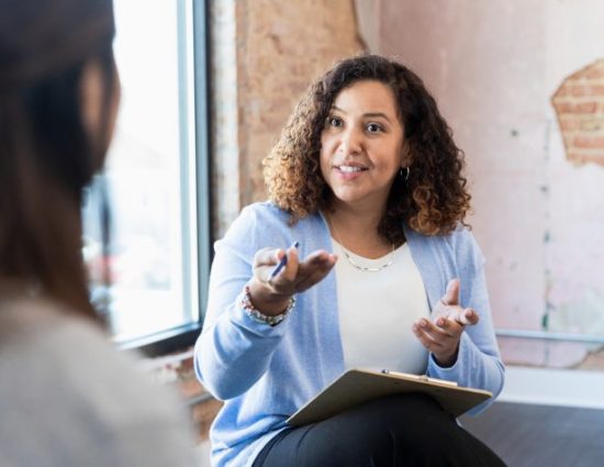 Woman with a clipboard talking to a coworker