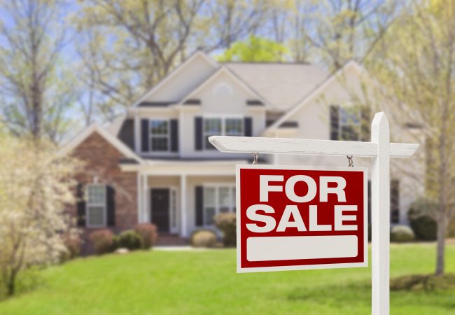For Sale sign in front of large house