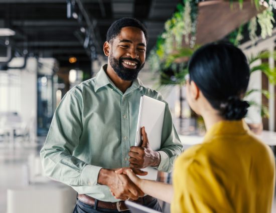 Two professionals shaking hands after accepting a new job offer, marking the start of the corporate relocation process.