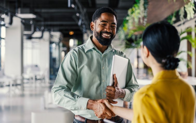 Two professionals shaking hands after accepting a new job offer, marking the start of the corporate relocation process.