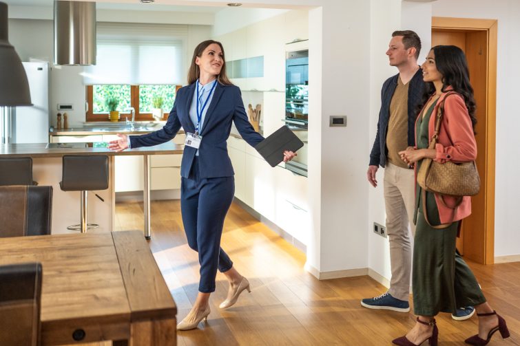 Real estate agent showing a home interior to a couple during a corporate relocation home search