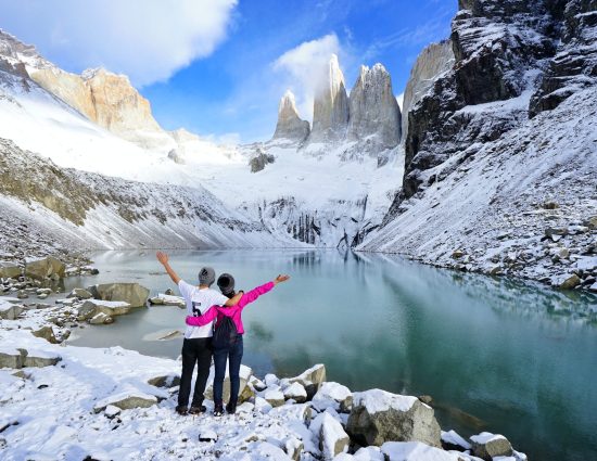 Two travelers overlooking a glacial lake and the Torres del Paine peaks in Chile