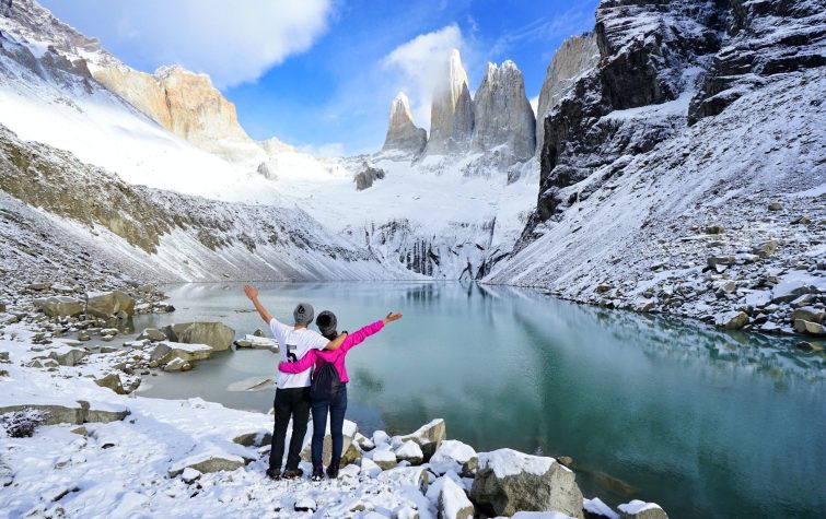 Two travelers overlooking a glacial lake and the Torres del Paine peaks in Chile